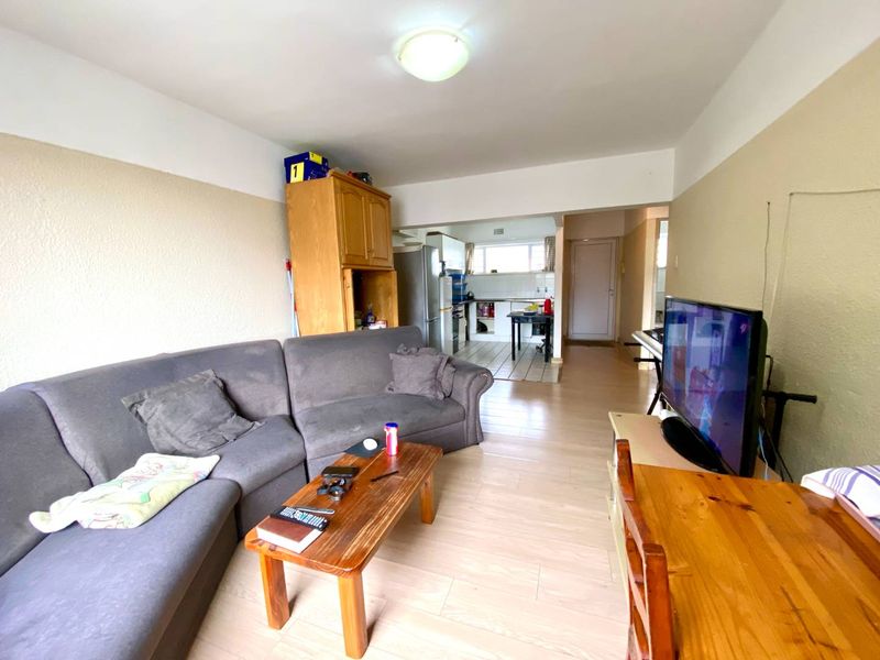 Open-plan living area featuring laminate flooring and a connected kitchen space with built-in cabinetry.