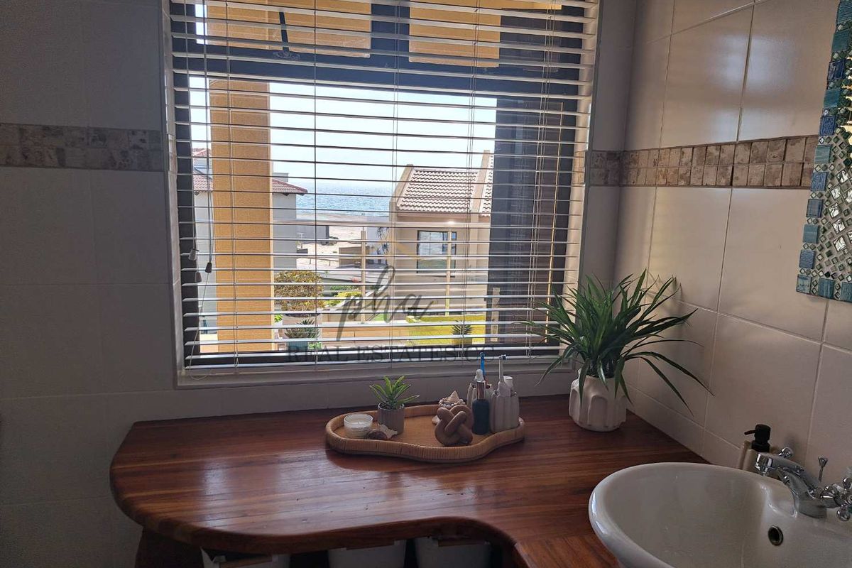 Bathroom vanity area featuring a custom wooden countertop, integrated basin, and a window with views of the surrounding estate and ocean.
