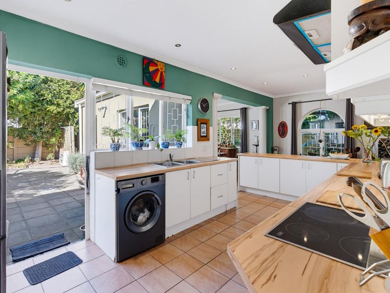 Spacious kitchen featuring white cabinetry, wooden countertops, integrated hob, and direct access to the rear patio area.