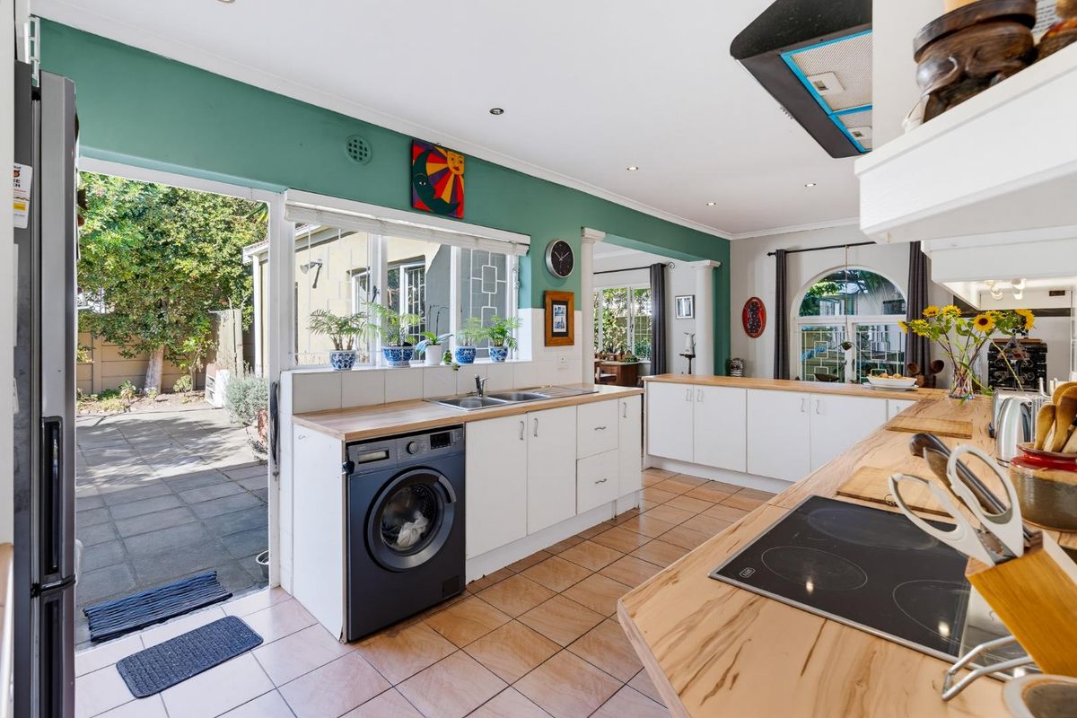 Spacious kitchen featuring white cabinetry, wooden countertops, integrated hob, and direct access to the rear patio area.
