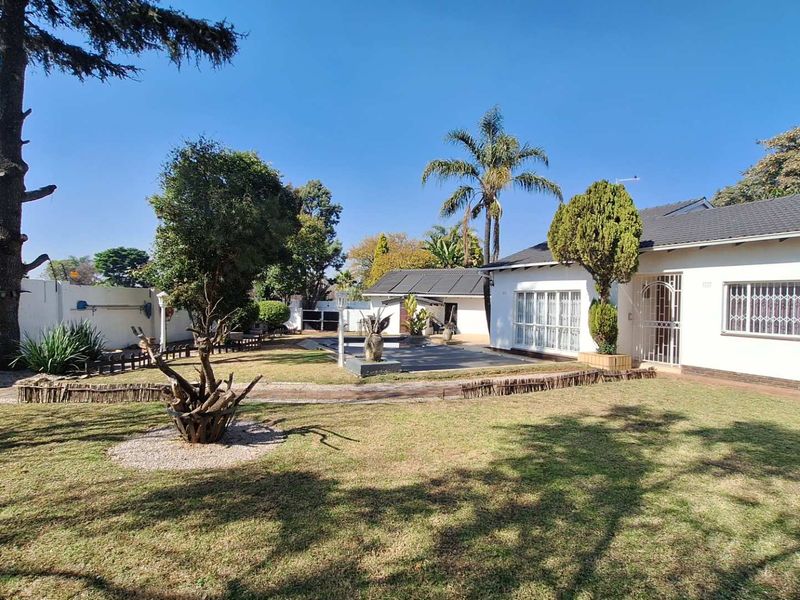 A spacious rear garden featuring a well-maintained lawn, paved patio area, and secure perimeter wall, providing a private outdoor space.