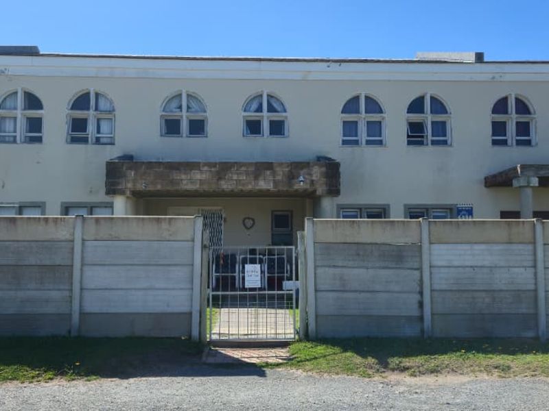 Front elevation of a two-story house featuring arched windows, a balcony, and a precast concrete boundary wall with a metal entrance gate.