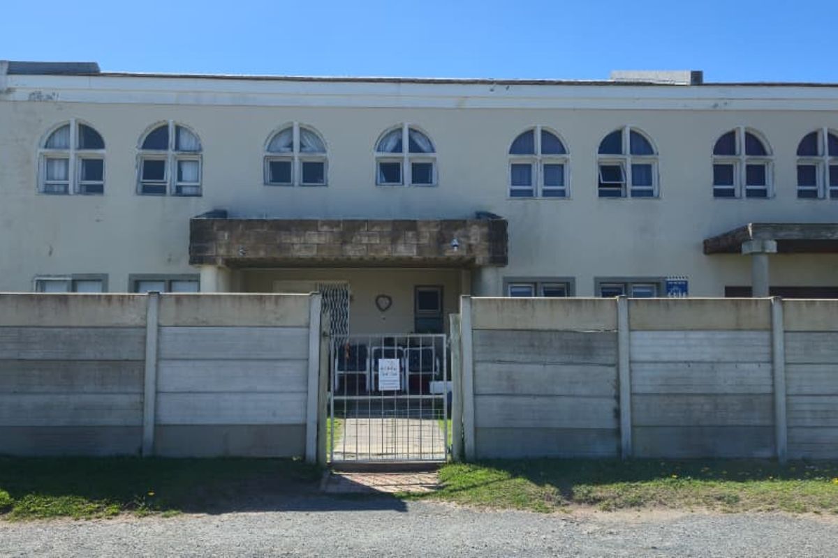 Front elevation of a two-story house featuring arched windows, a balcony, and a precast concrete boundary wall with a metal entrance gate.