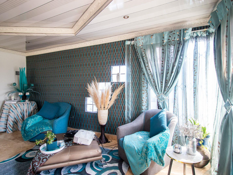 A living room featuring patterned wallpaper, tiled flooring, and a coffered ceiling with integrated lighting.