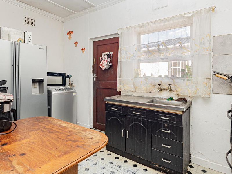 A dated kitchen featuring original cabinetry, a stainless steel sink, and tiled flooring, offering significant potential for modernization and renovation.