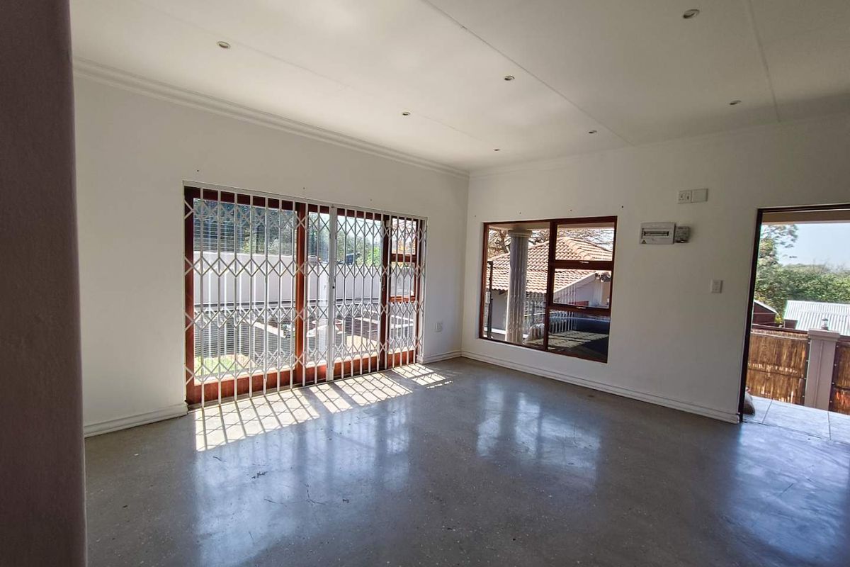Spacious, empty living area featuring polished concrete floors, recessed lighting, and large sliding doors with security gates leading to the exterior.