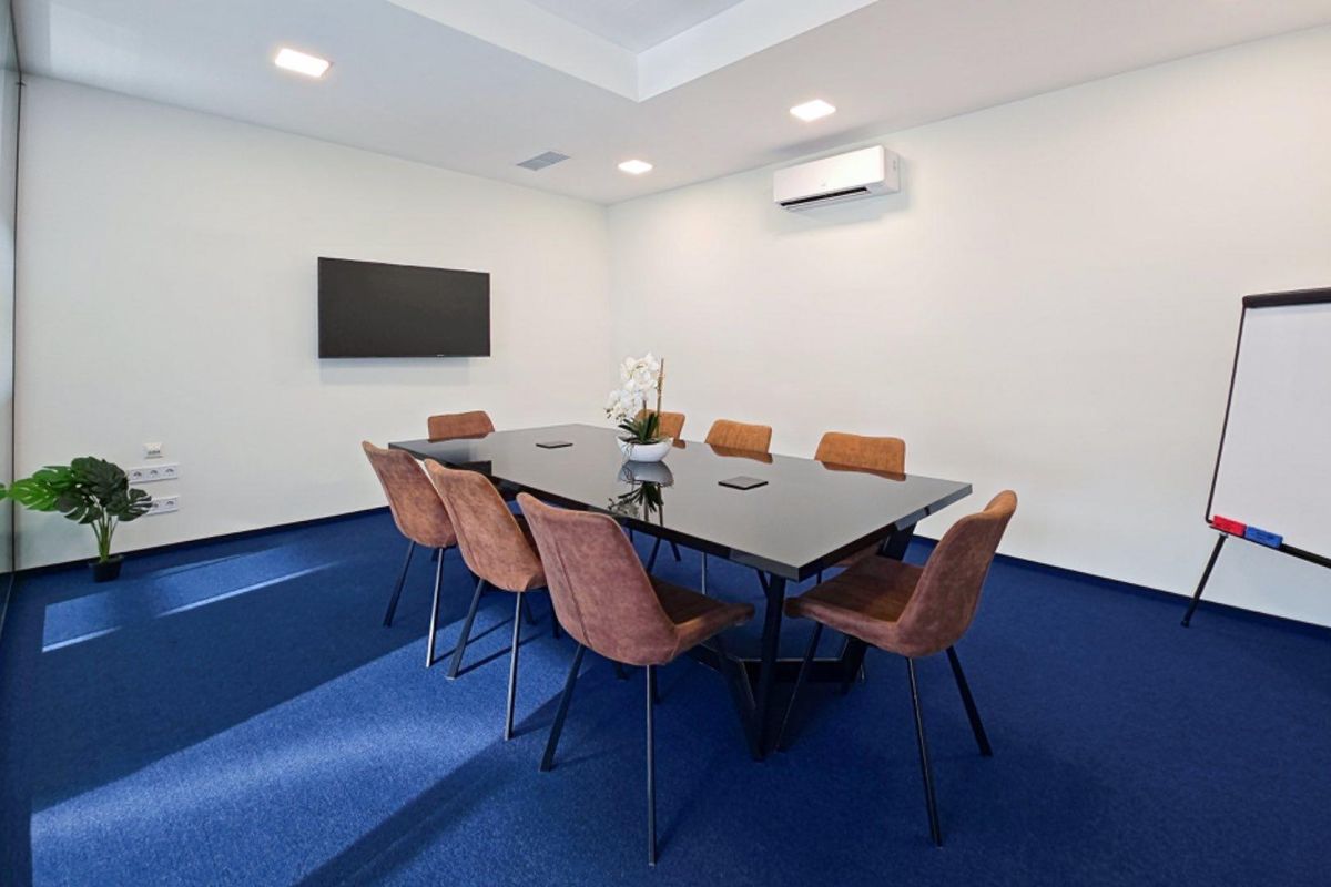 A professional office meeting room featuring a central conference table, wall-mounted television, and integrated air conditioning system.