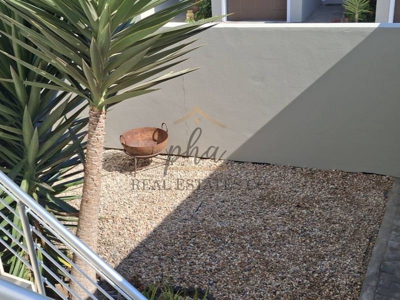 A low-maintenance rear courtyard area featuring gravel landscaping, a secure boundary wall, and a pedestrian gate, viewed from an elevated position.