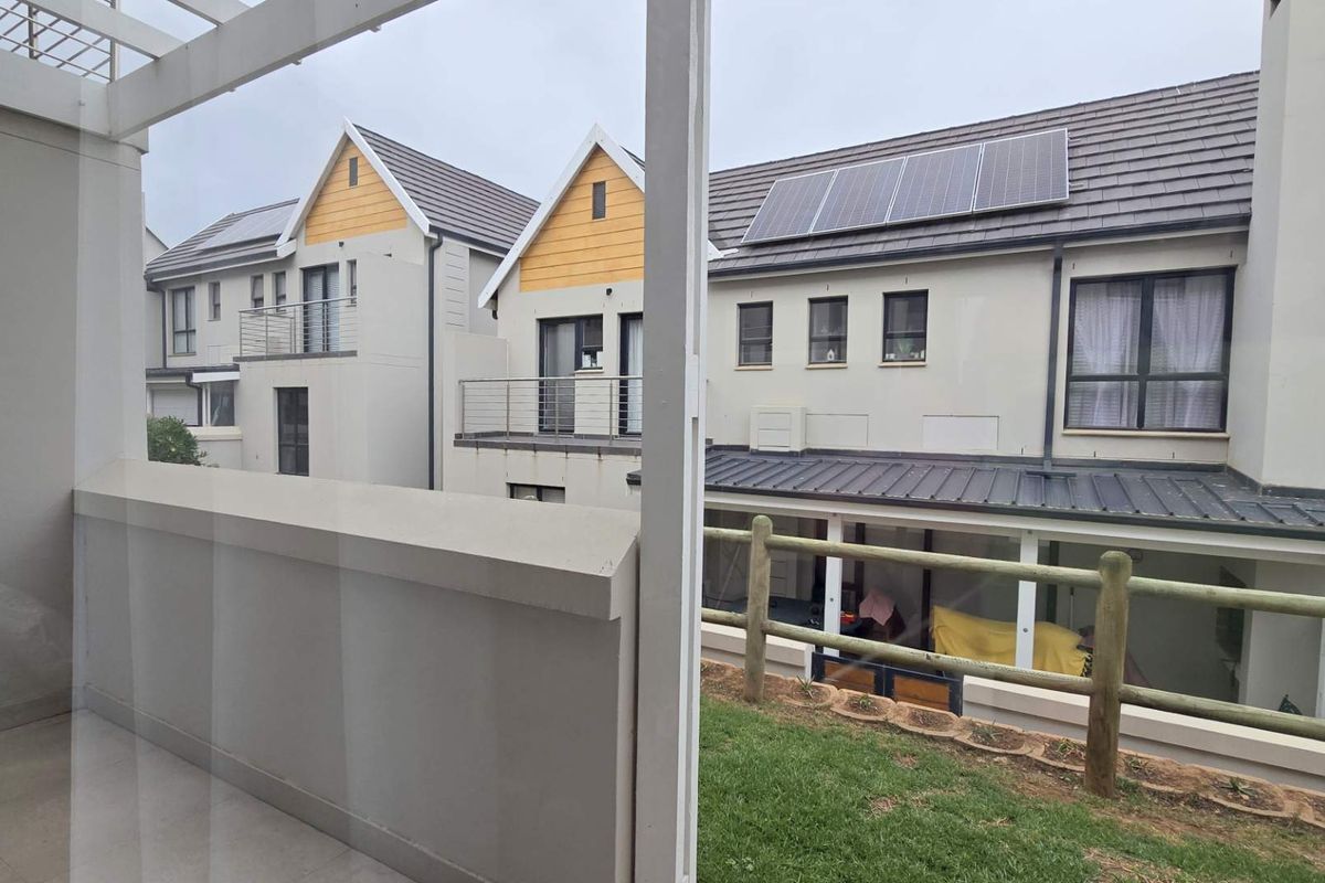 View of the rear exterior of the apartment complex, featuring modern architecture, tiled roofing, and installed solar panels.