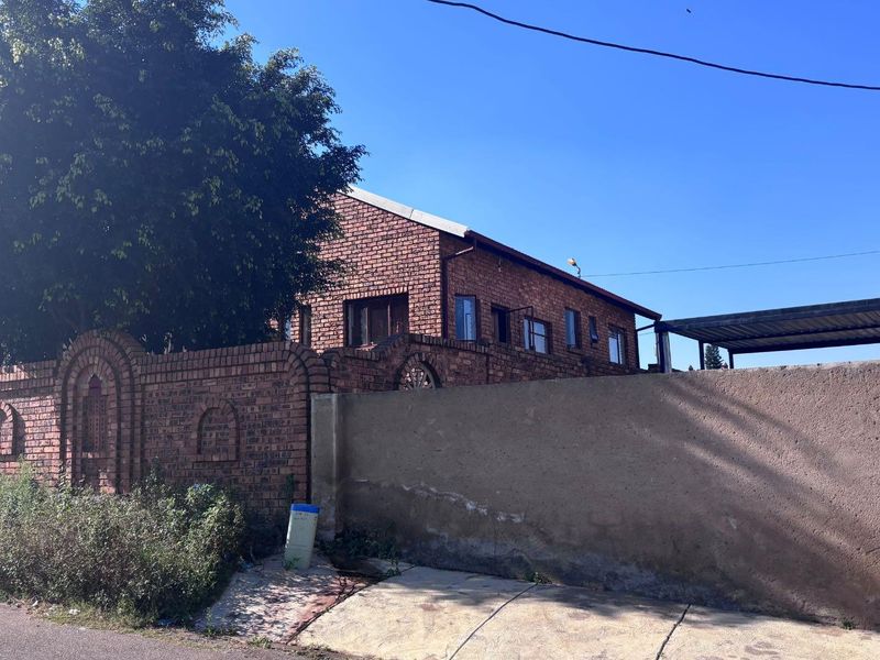 Street view of a face brick house featuring a combination of face brick and plastered boundary walls with an attached carport.