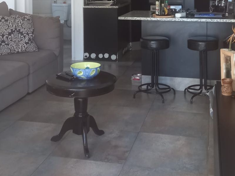 Open plan living area featuring a kitchen with granite countertops and built-in oven, seamlessly connected to the lounge space with large format floor tiles.