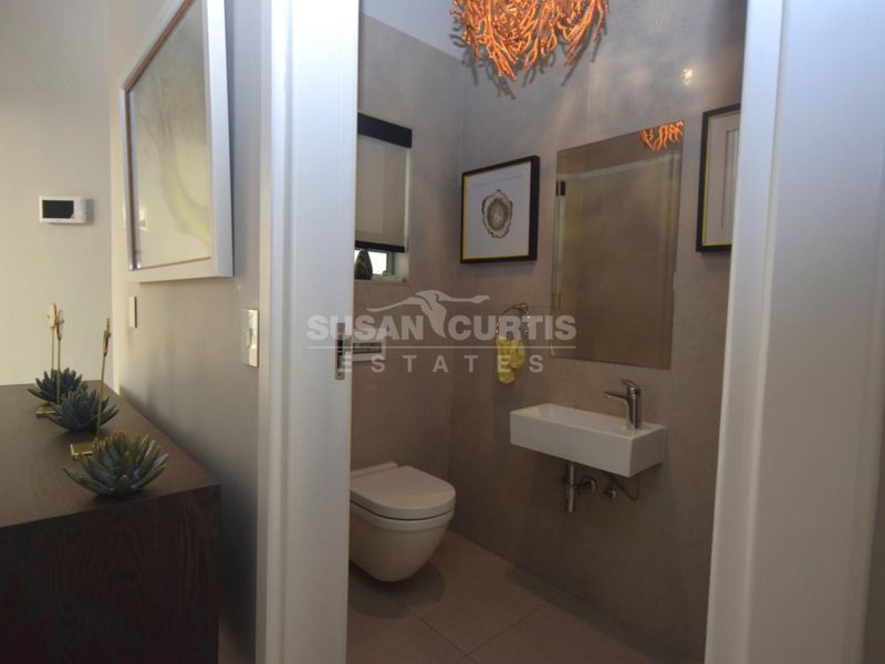 A compact guest bathroom featuring a modern wall-hung toilet and a sleek wall-mounted basin with neutral tiling.