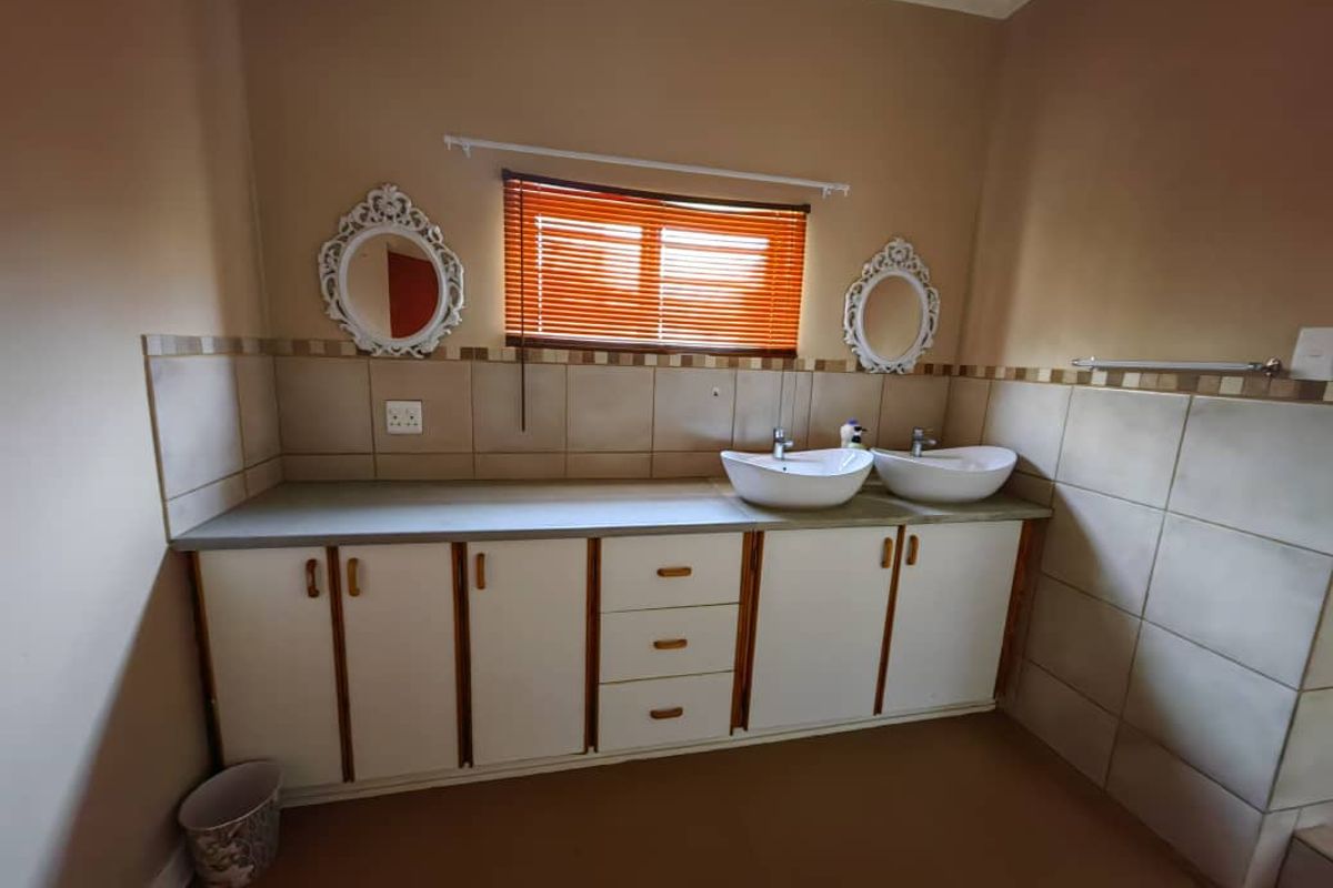 A functional bathroom featuring a double vanity with vessel sinks, built-in cabinetry, and tiled splashback, offering a practical layout with potential for modern updates.