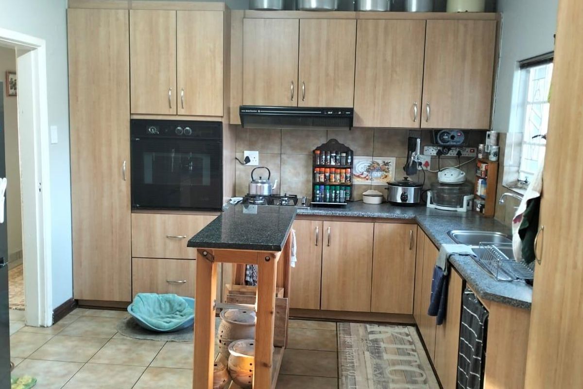 A functional kitchen featuring light wood-tone cabinetry, granite-look countertops, a built-in oven, and a gas hob with an extractor fan.
