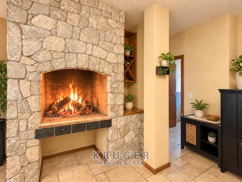 A cozy living area featuring a prominent stone fireplace with a built-in wine rack and neutral tiled flooring.