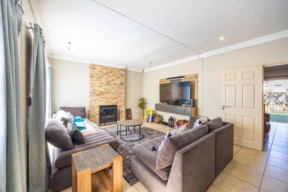 A comfortable living room featuring a stone-clad fireplace, tiled flooring, and a built-in media console, offering a warm and functional space.
