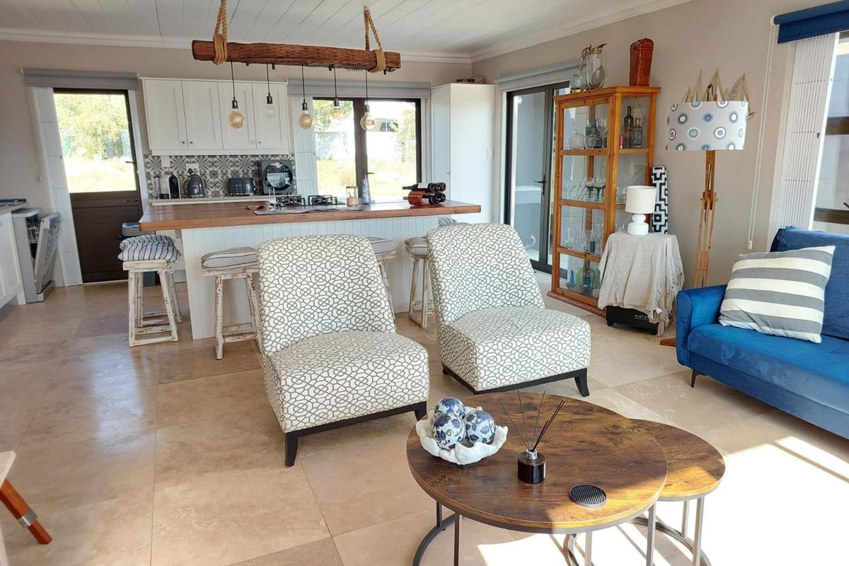 Spacious open-plan living area featuring a modern kitchen with a timber-topped island, stone tile flooring, and direct access to outdoor spaces.