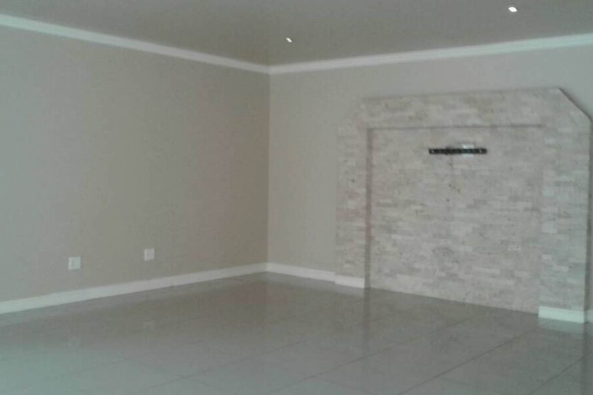 Spacious living area featuring a decorative stone-clad feature wall and polished tile flooring with recessed ceiling lighting.