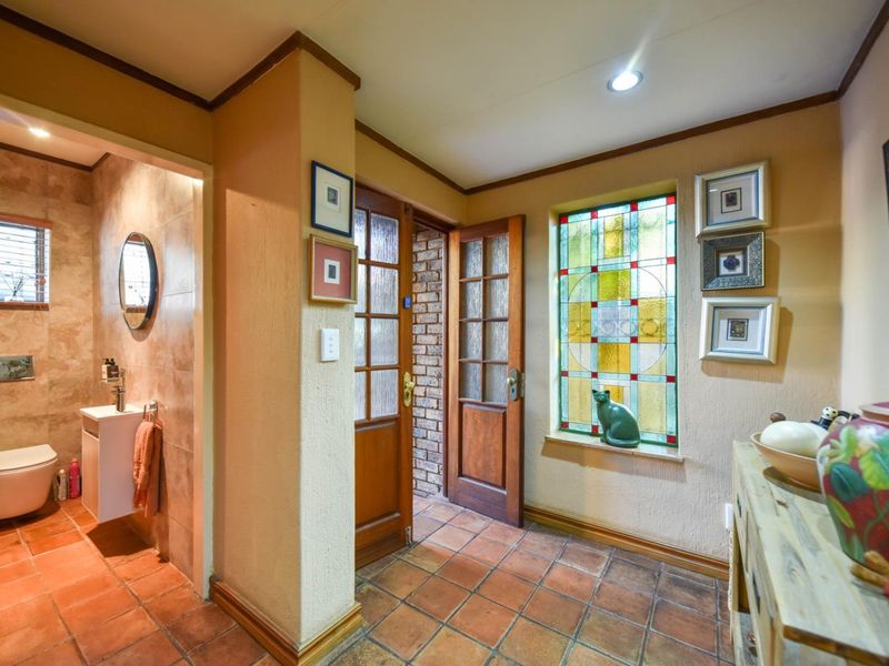 Welcoming entry foyer featuring terracotta floor tiles, a decorative stained glass window, and direct access to a modern tiled bathroom with wall-hung fixtures.