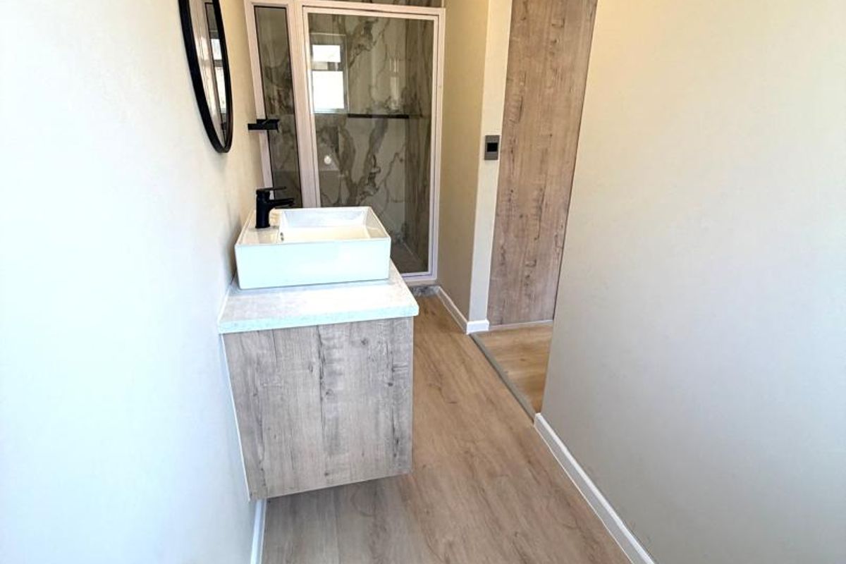 Modern bathroom featuring a floating vanity with a vessel sink, a walk-in shower with marble-look tiling, and wood-look flooring.