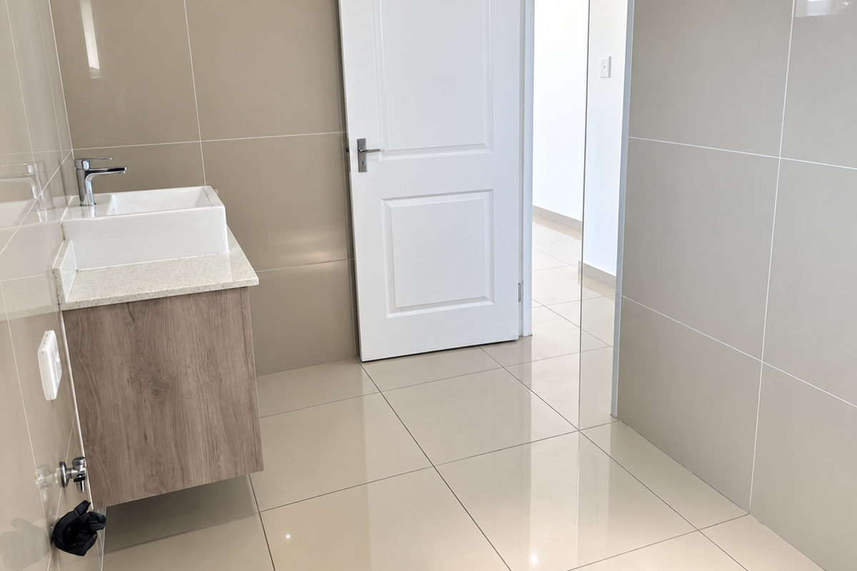 A modern, minimalist bathroom featuring a wall-mounted vanity with a vessel sink, stone countertop, and neutral large-format ceramic tiling throughout.