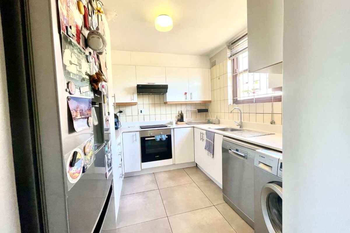 A functional kitchen featuring white cabinetry, tiled backsplash, built-in oven and hob, and tiled flooring with space for integrated appliances.