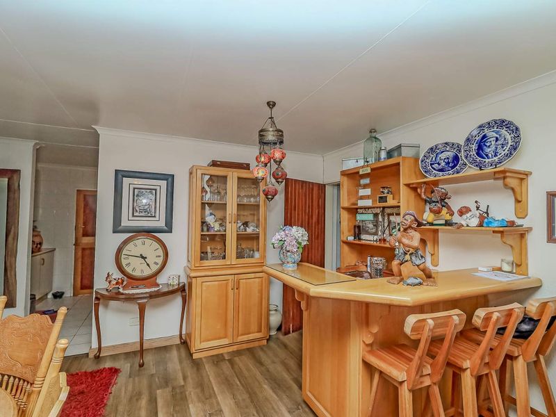 A dedicated bar area featuring a built-in wooden counter, integrated shelving, and laminate flooring, providing a functional space for entertaining.
