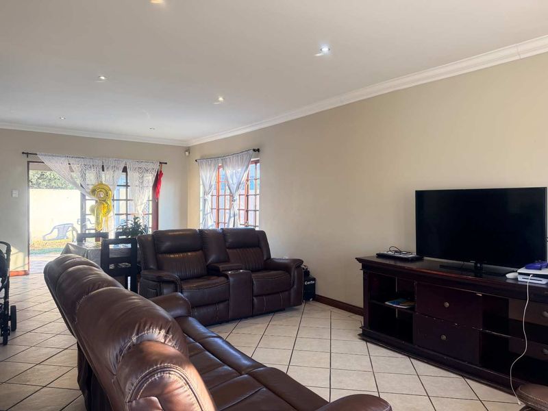 Spacious living room featuring ceramic tiled flooring, recessed downlighting, and direct access to the rear patio through timber-framed sliding doors.
