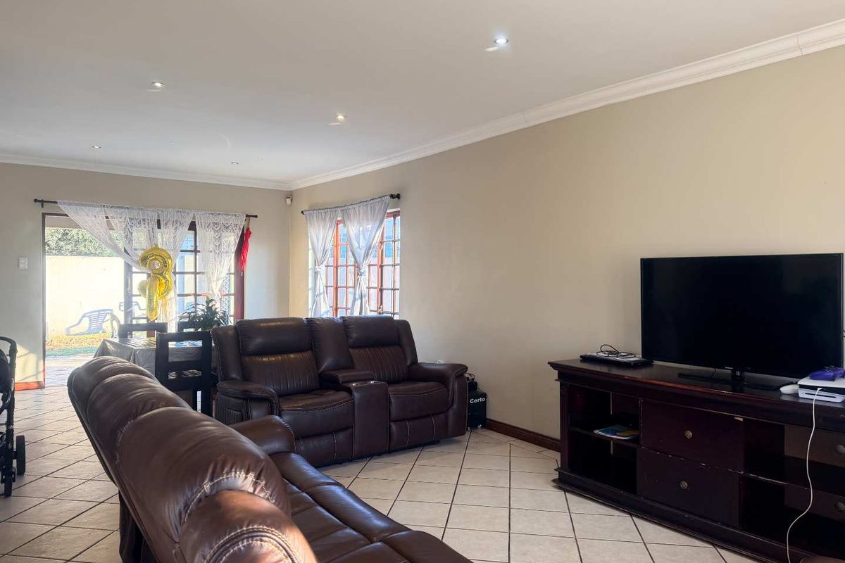 Spacious living room featuring ceramic tiled flooring, recessed downlighting, and direct access to the rear patio through timber-framed sliding doors.
