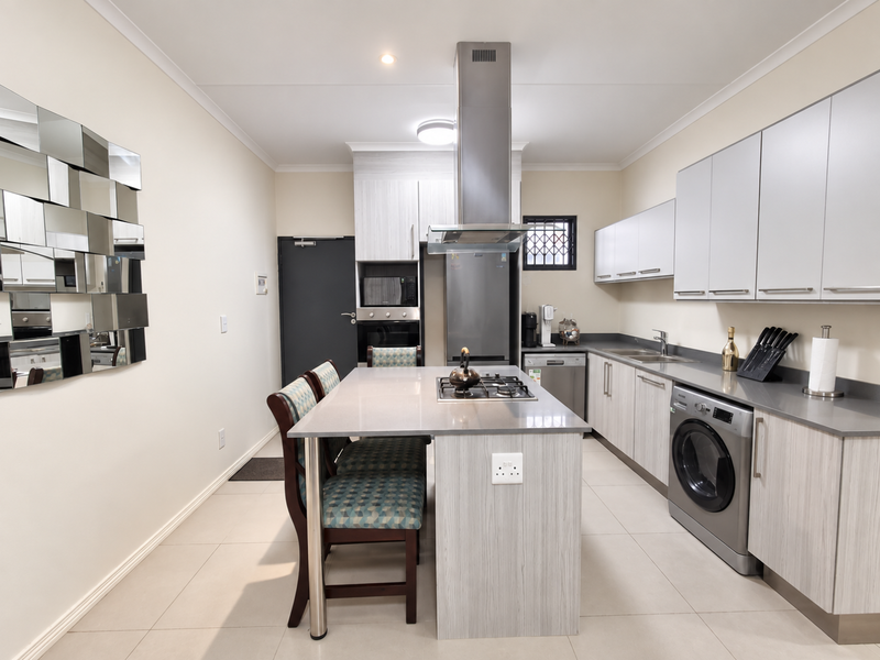 Modern kitchen featuring a central island with a gas hob, built-in appliances, sleek cabinetry, and tiled flooring.