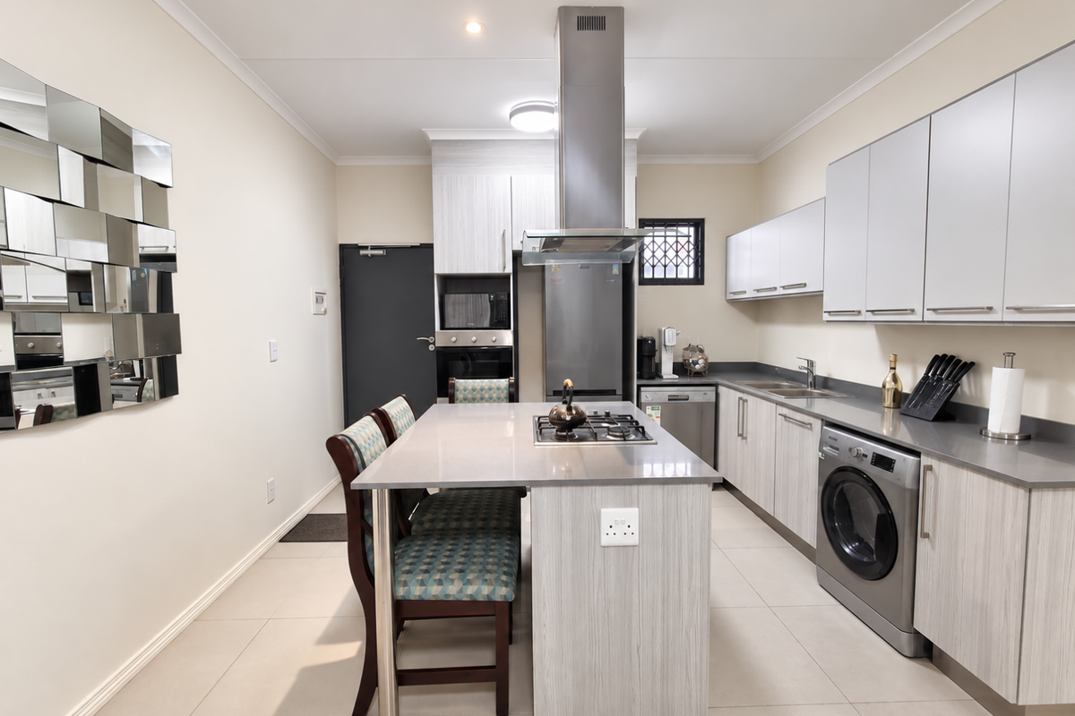 Modern kitchen featuring a central island with a gas hob, built-in appliances, sleek cabinetry, and tiled flooring.
