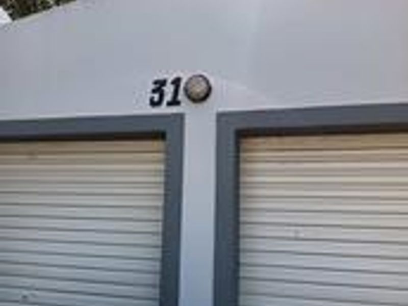 Exterior view of a garage unit featuring two roller shutter doors and a mounted exterior light fixture.