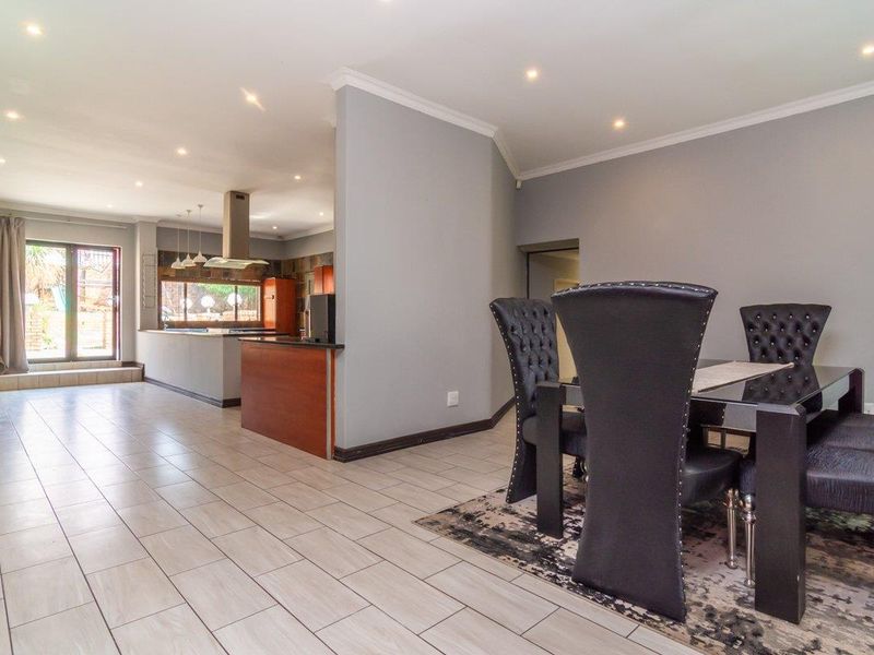 Spacious open-plan living and dining area featuring modern tiled flooring, recessed lighting, and a functional kitchen with a central island and extractor fan.