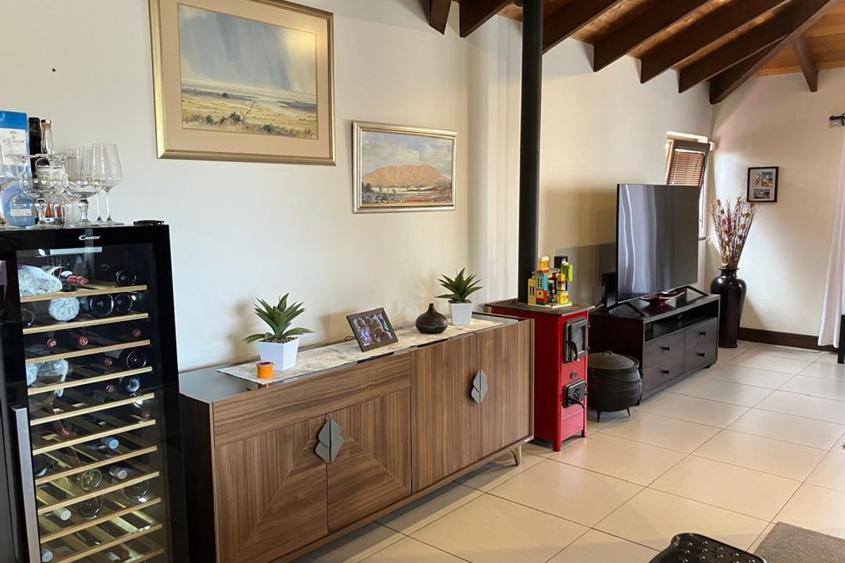 A living room featuring exposed timber ceiling beams, tiled flooring, and a prominent red freestanding fireplace, creating a warm and inviting atmosphere.