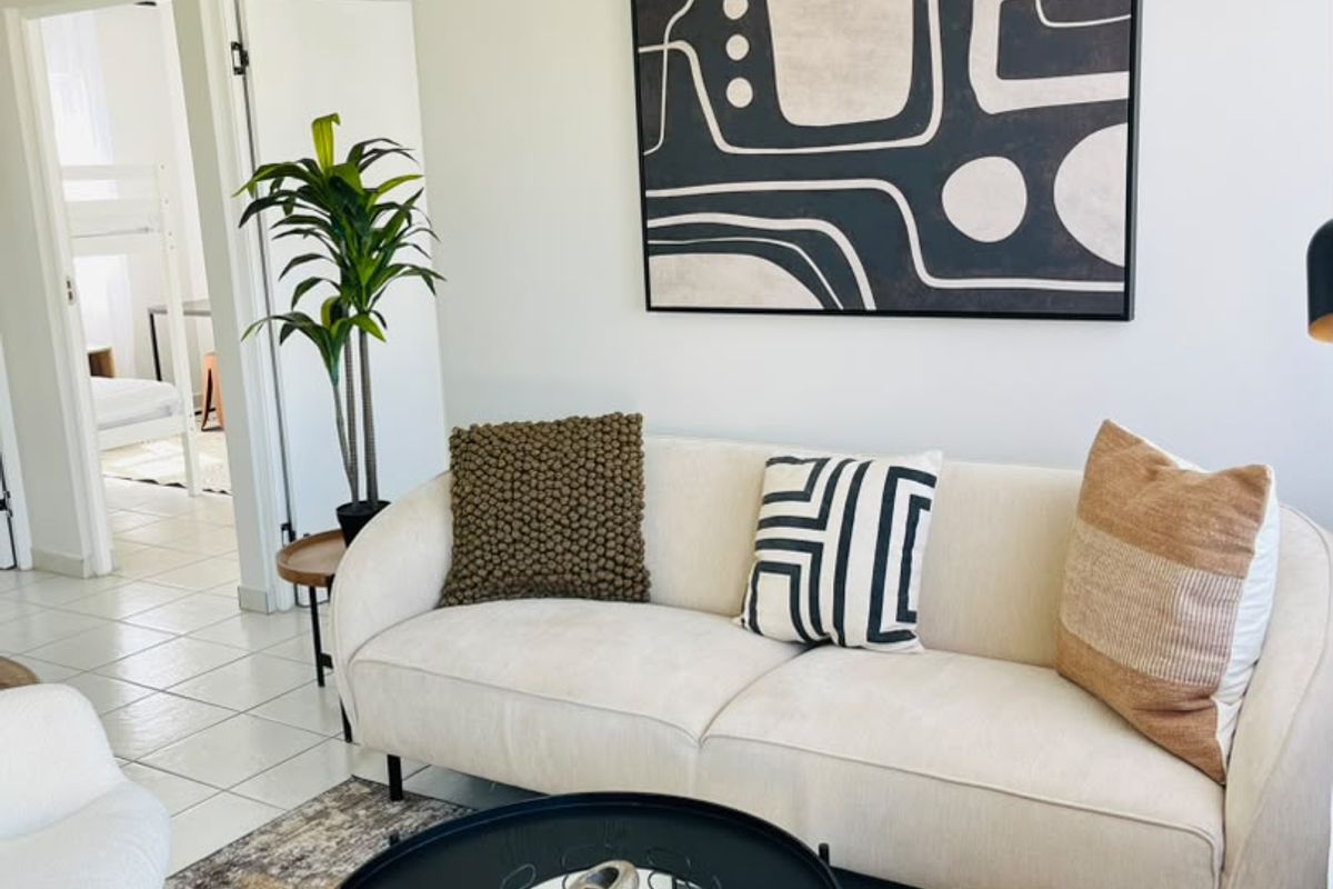 A bright and well-maintained living room featuring neutral walls, tiled flooring, and clear access to adjacent rooms.