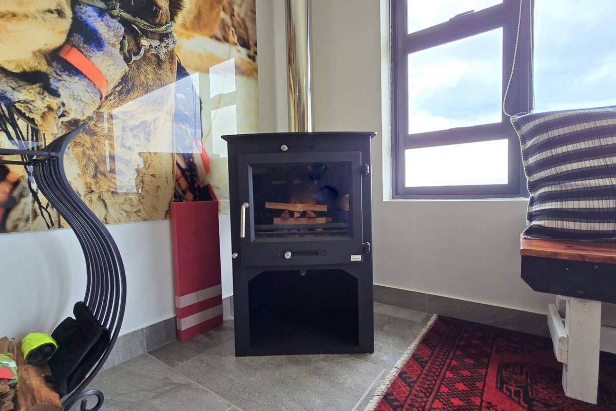 A cozy living area featuring a modern black freestanding wood-burning fireplace with a stainless steel flue and tiled flooring.