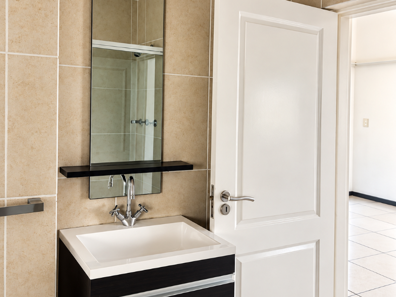 A modern bathroom featuring a wall-mounted vanity with an integrated basin, chrome fixtures, and neutral wall tiling.
