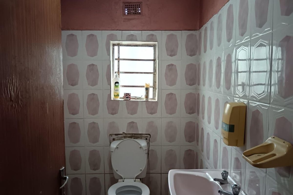A dated bathroom featuring a pedestal basin, toilet, and patterned wall tiles, requiring modernization and cosmetic updates to improve functionality and aesthetic appeal.