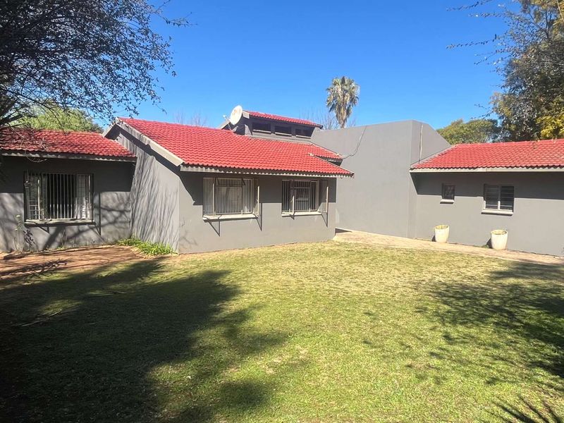 A view of the rear exterior of the house featuring a red tiled roof, grey painted walls, and a well-maintained lawn.