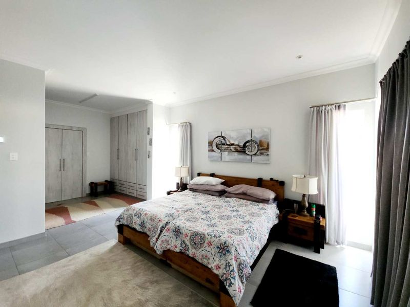 Spacious bedroom featuring neutral tiled flooring, extensive built-in cabinetry, and direct access to an outdoor area through a sliding door.