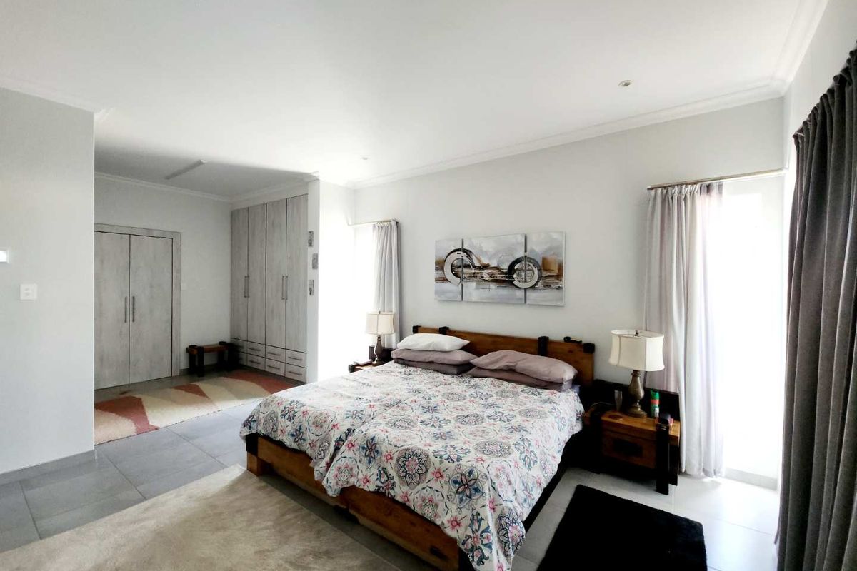 Spacious bedroom featuring neutral tiled flooring, extensive built-in cabinetry, and direct access to an outdoor area through a sliding door.