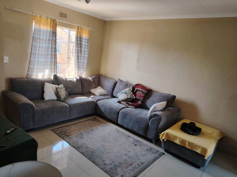 A living room featuring tiled flooring and neutral wall tones, offering a functional space with natural light from the window.