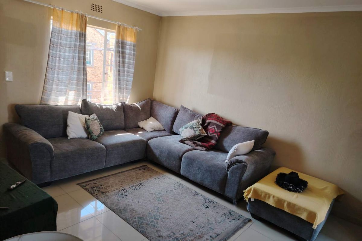 A living room featuring tiled flooring and neutral wall tones, offering a functional space with natural light from the window.