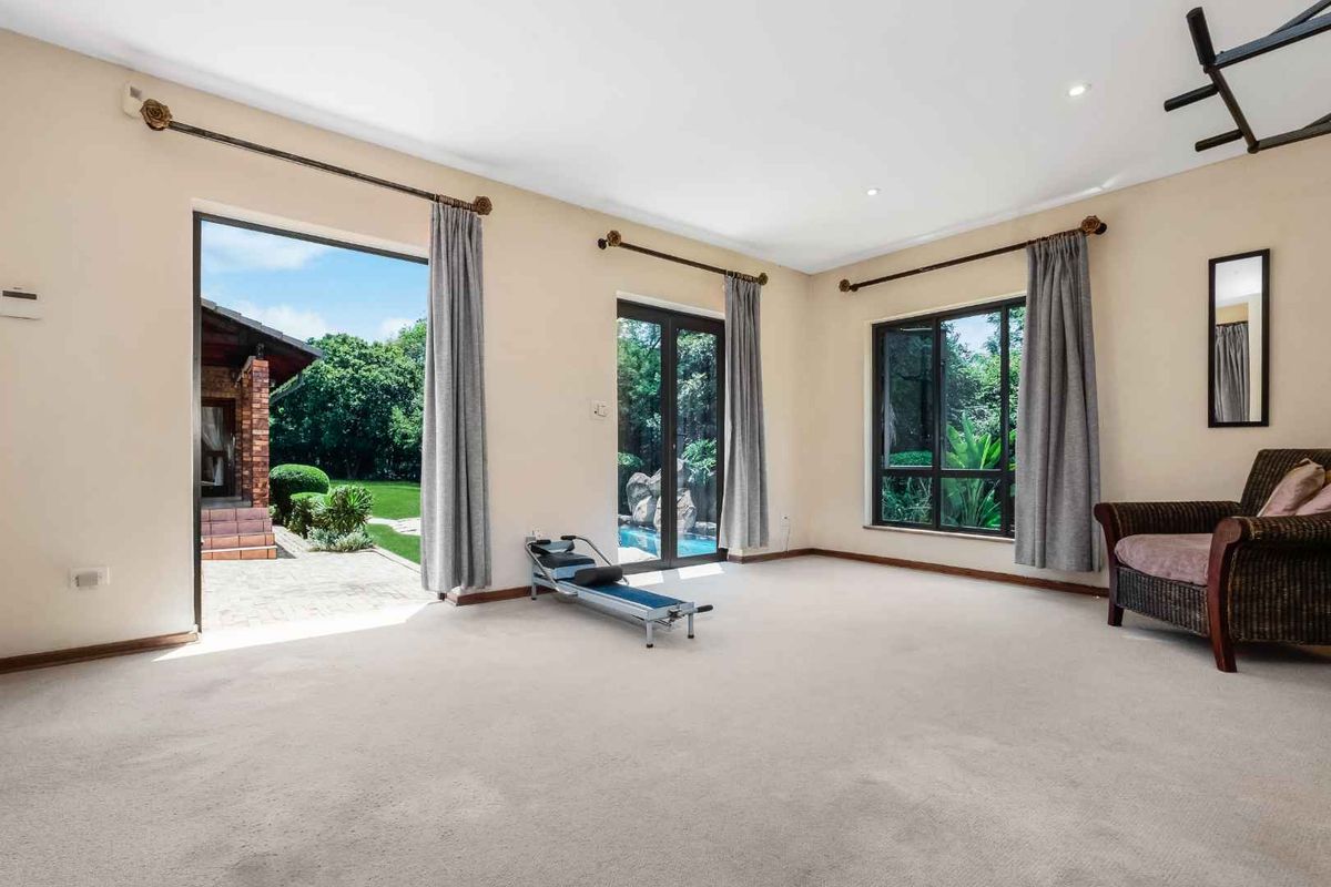 Spacious living area featuring neutral carpeting, recessed lighting, and multiple glass doors providing direct access to the outdoor patio and pool area.
