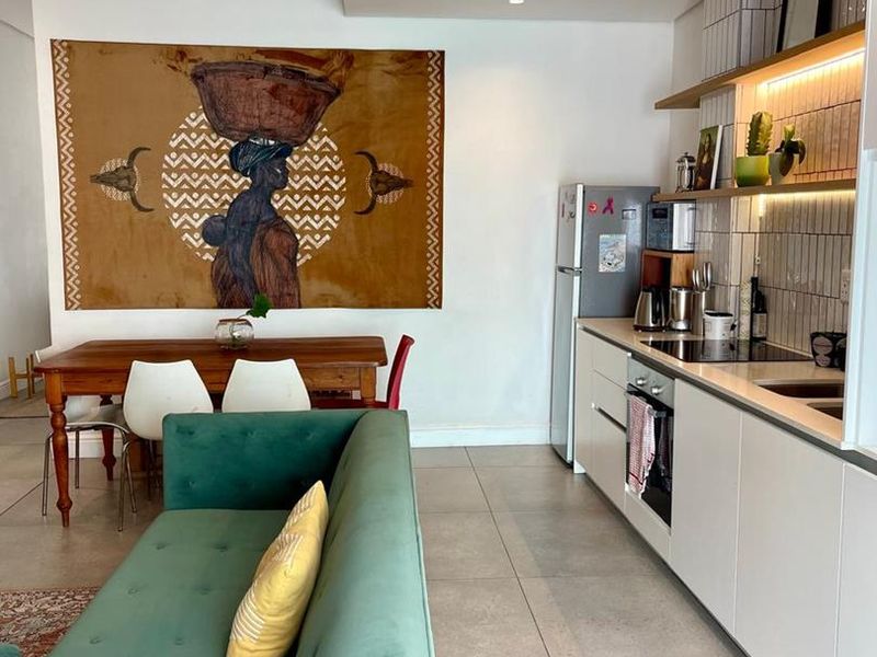 Modern open-plan living area featuring a sleek kitchen with built-in cabinetry, integrated appliances, tiled backsplash, and recessed lighting, seamlessly connected to the dining space.
