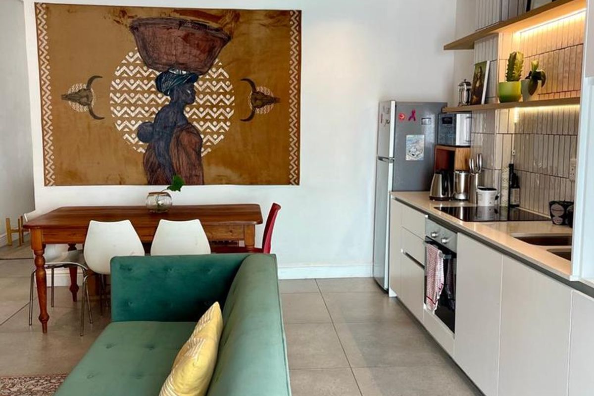 Modern open-plan living area featuring a sleek kitchen with built-in cabinetry, integrated appliances, tiled backsplash, and recessed lighting, seamlessly connected to the dining space.