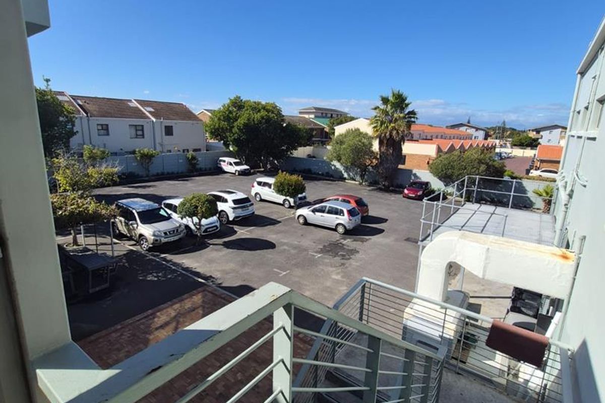 An elevated view of the rear exterior parking area, featuring a metal staircase with railings and external building ventilation infrastructure.