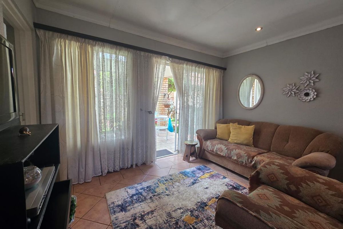 A cozy living room featuring tiled flooring, coved ceilings, and a sliding glass door providing direct access to the outdoor patio area.