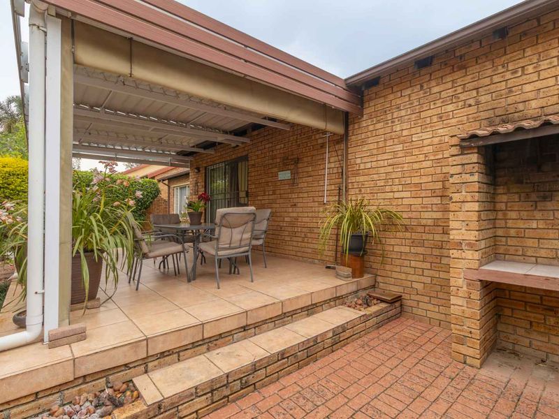 Covered outdoor patio featuring a built-in braai, tiled flooring, and direct access to the garden area.