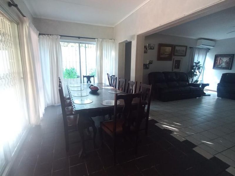 Open plan dining and living area featuring tiled flooring, coved ceilings, and large sliding glass doors providing access to the exterior.